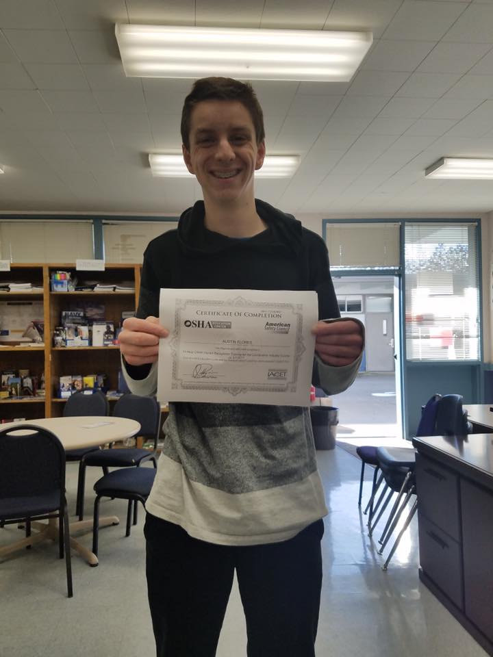 A young man proudly displaying a certificate in a classroom at The LIME Foundation of Santa Rosa.