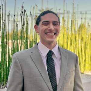 A man in a suit smiles in front of plants at a Sonoma County non-profit organization.
