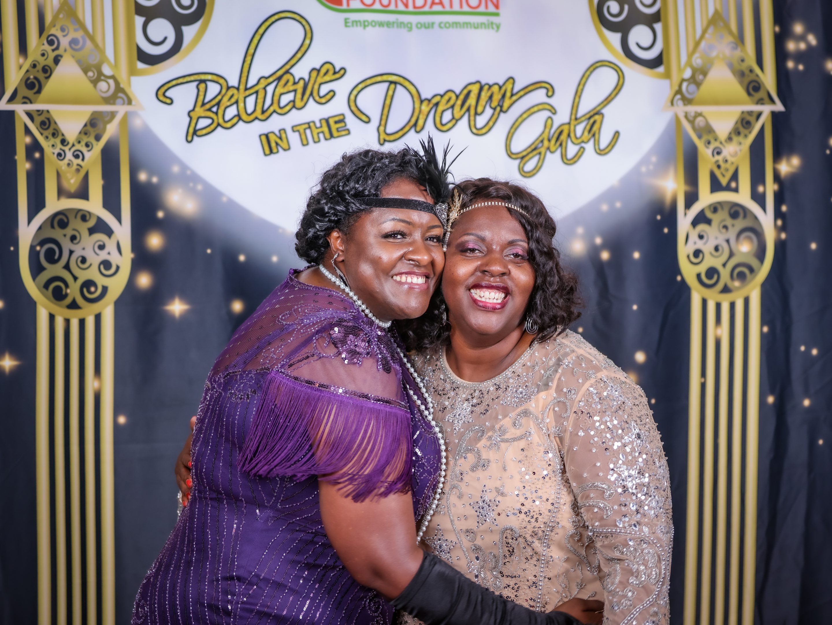 Two women dressed in 1920's attire pose for a photo at a themed party.