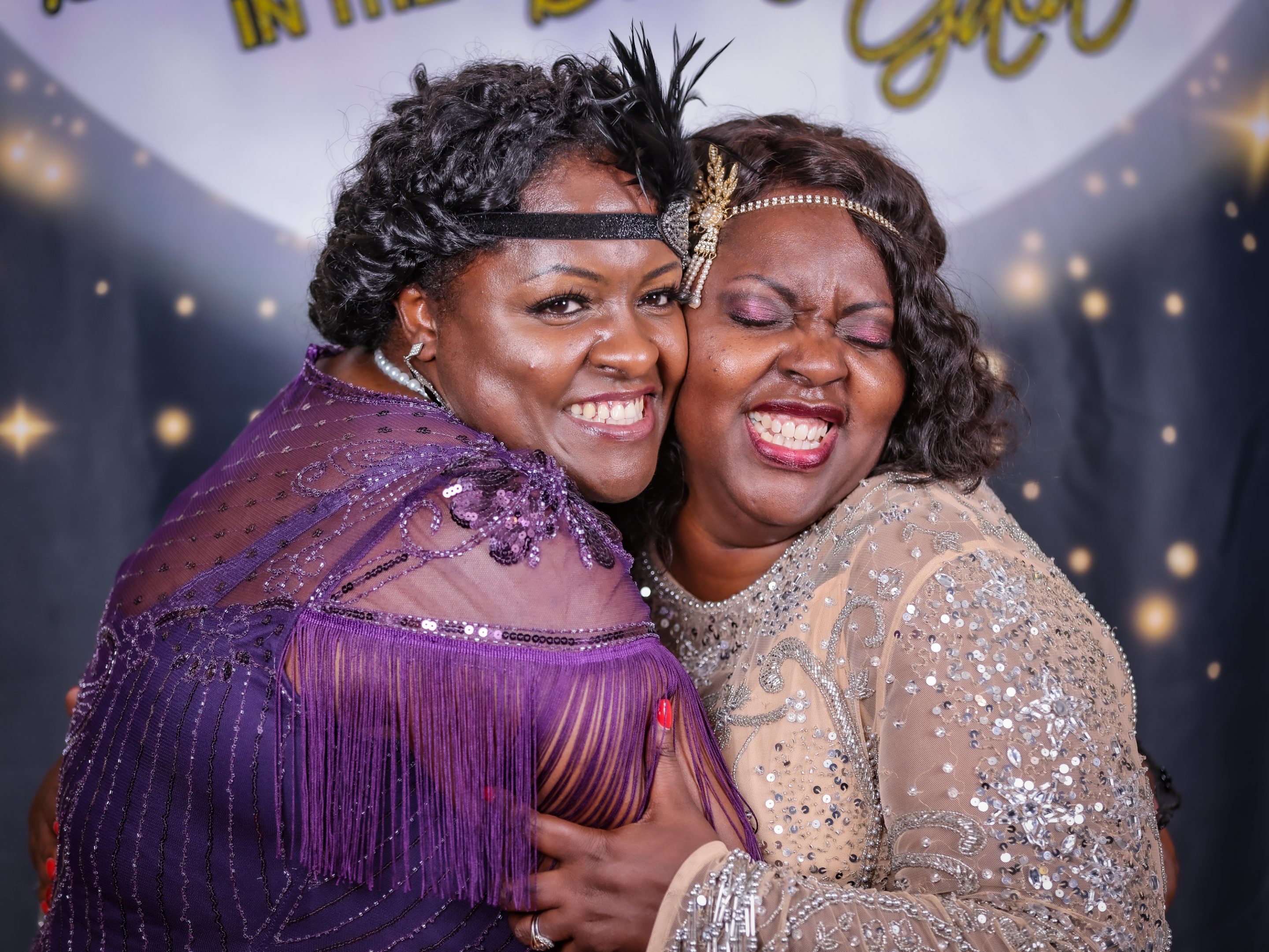 Two women hugging in front of a photo booth at a Sonoma County Non-Profit Organization event hosted by The LIME Foundation.