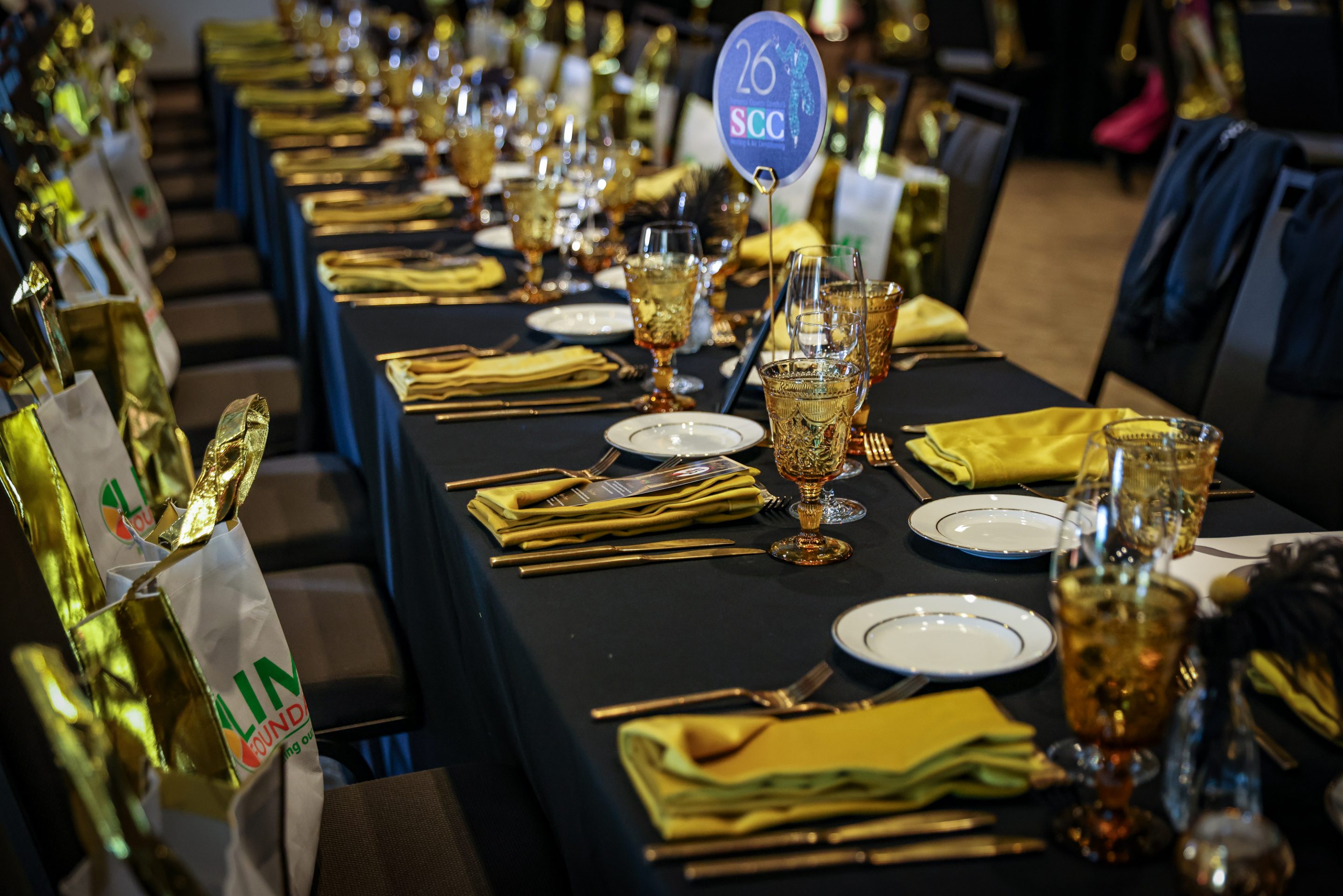 A black table set with gold plates for a Santa Rosa Non-Profit event.