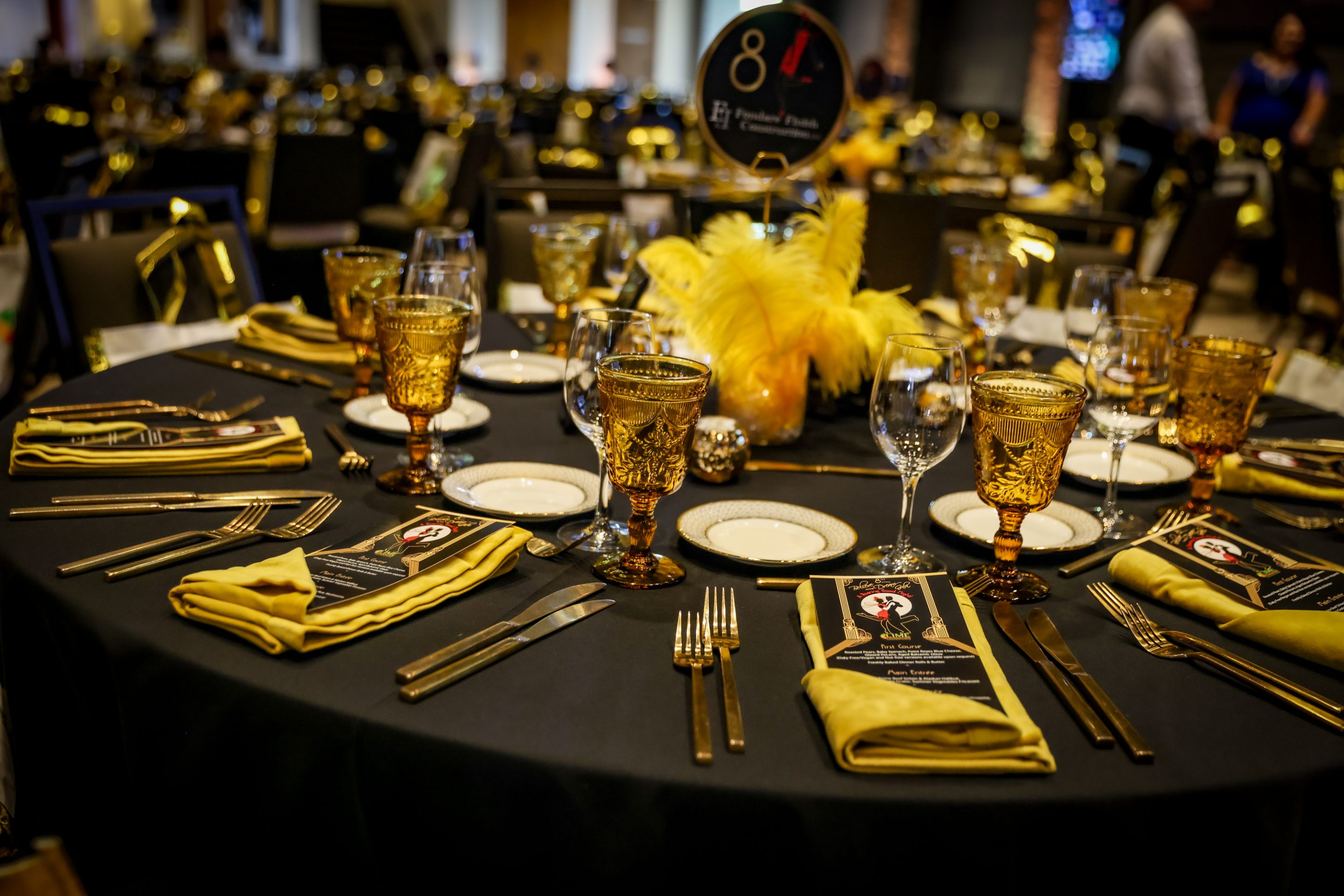 A black table setting with gold plates and silverware.
