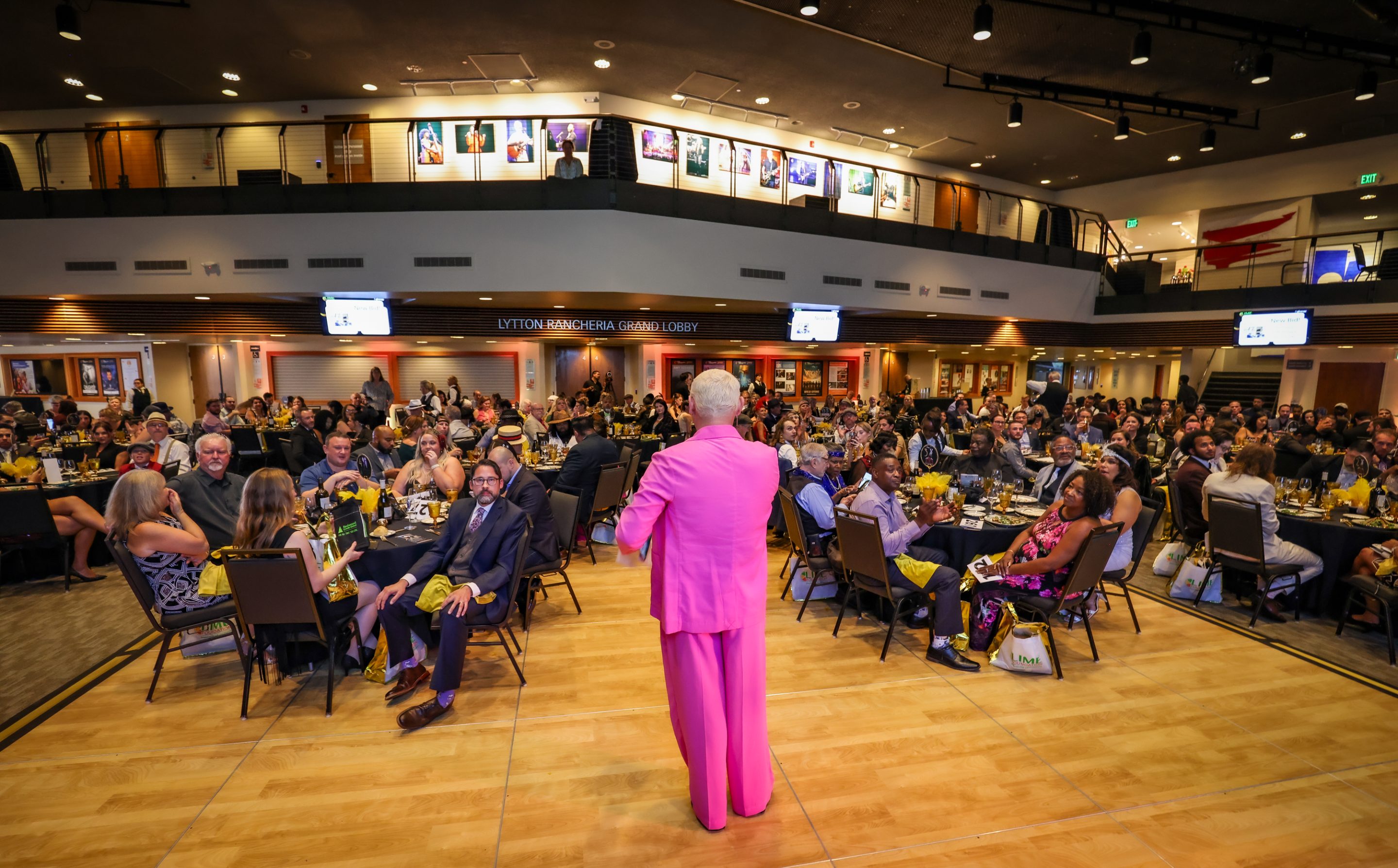 A woman in a pink suit standing in front of a large crowd at The LIME Foundation of Santa Rosa.