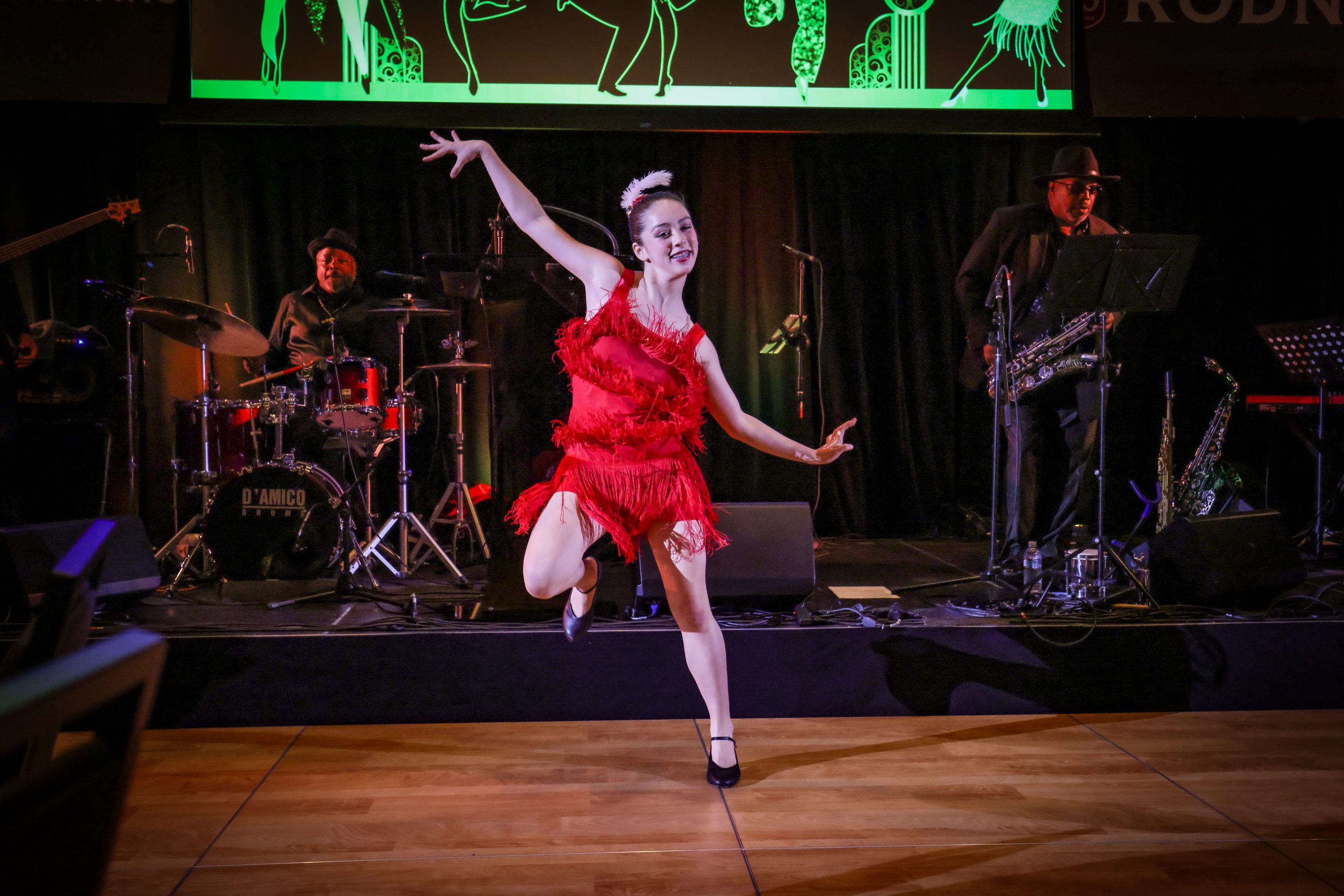 A woman in a red dress dancing on stage at a Santa Rosa Non-Profit event.