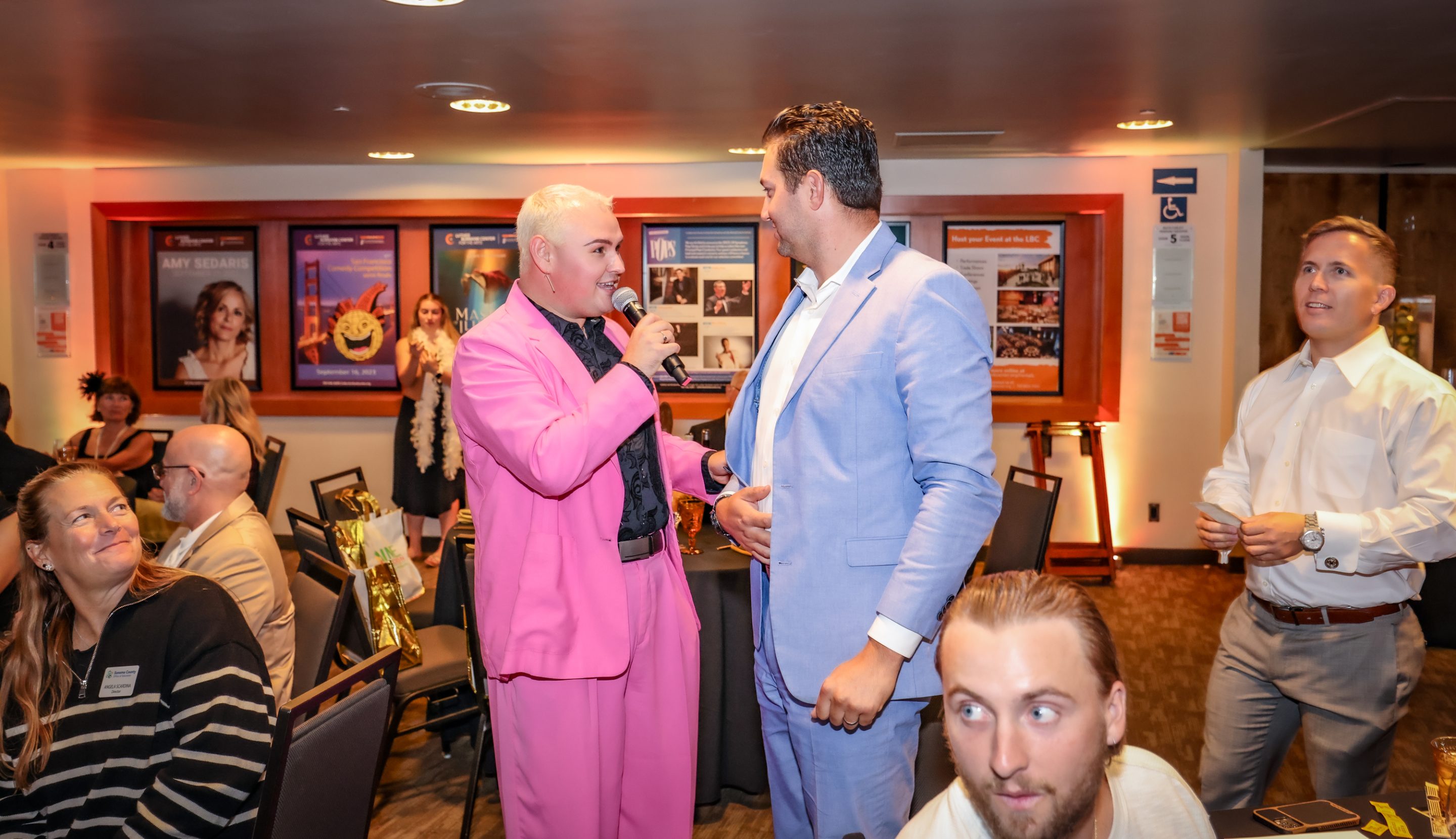 At a party, a man in a pink suit is chatting with another man from a Sonoma County Non-Profit organization.