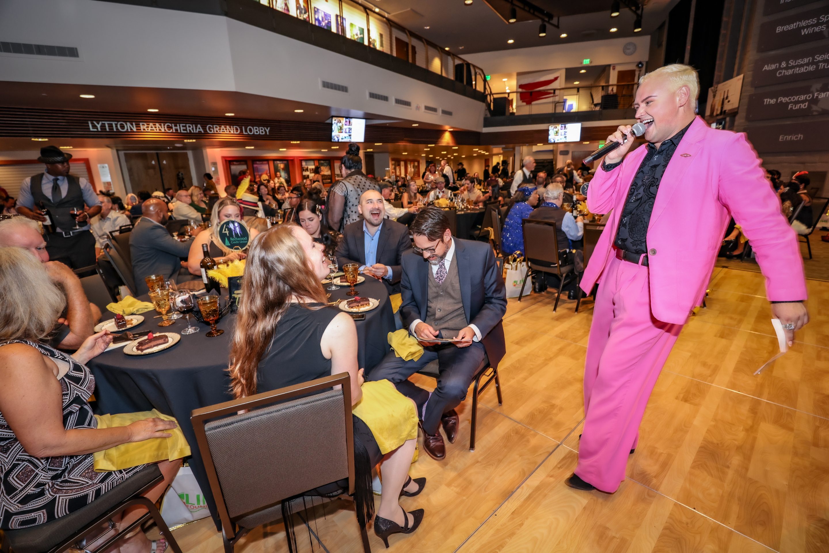 A man in a pink suit performing for a crowd at The LIME Foundation fundraiser.