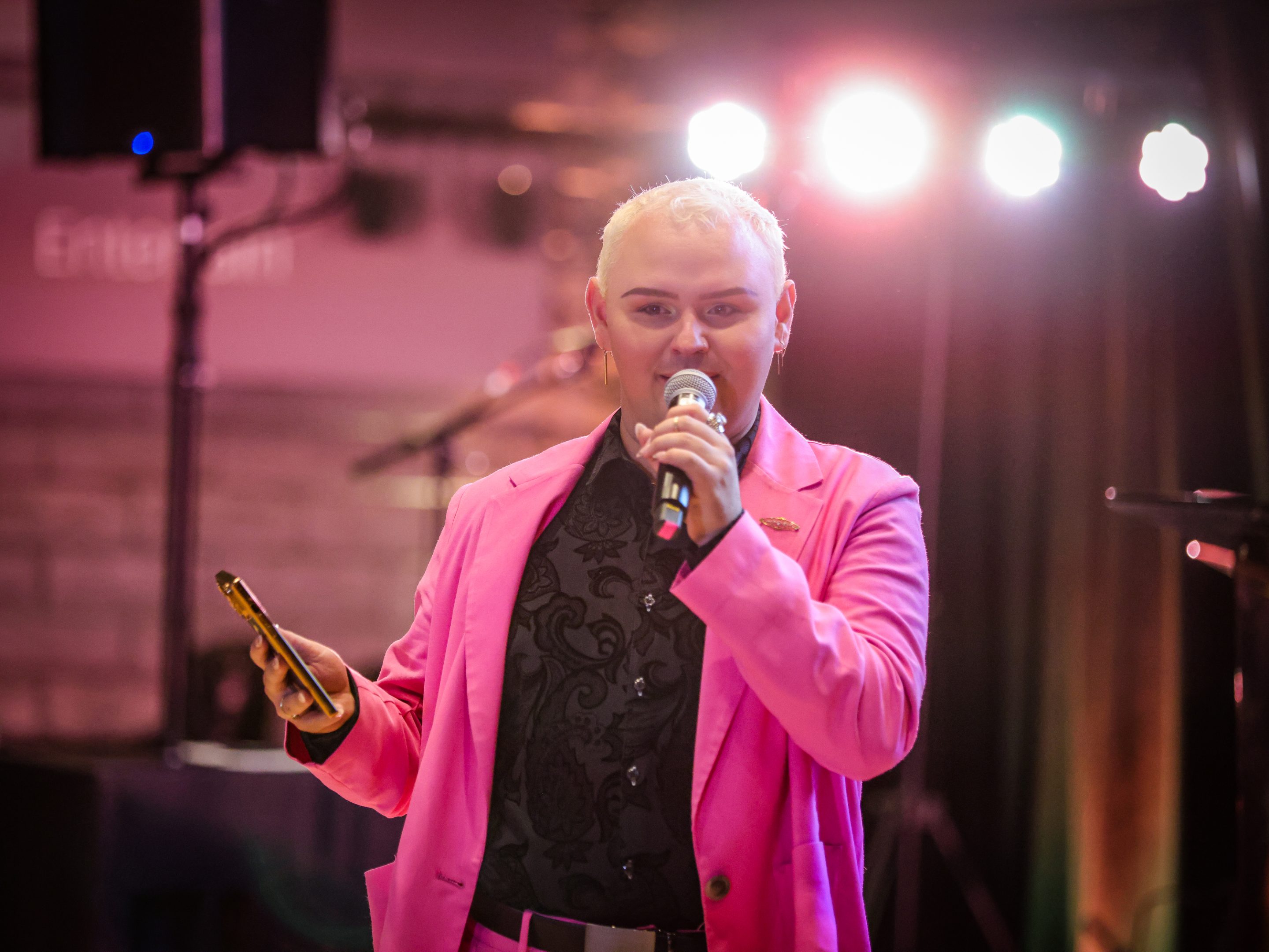 A man in a pink suit, representing The LIME Foundation of Santa Rosa, confidently holds a microphone.