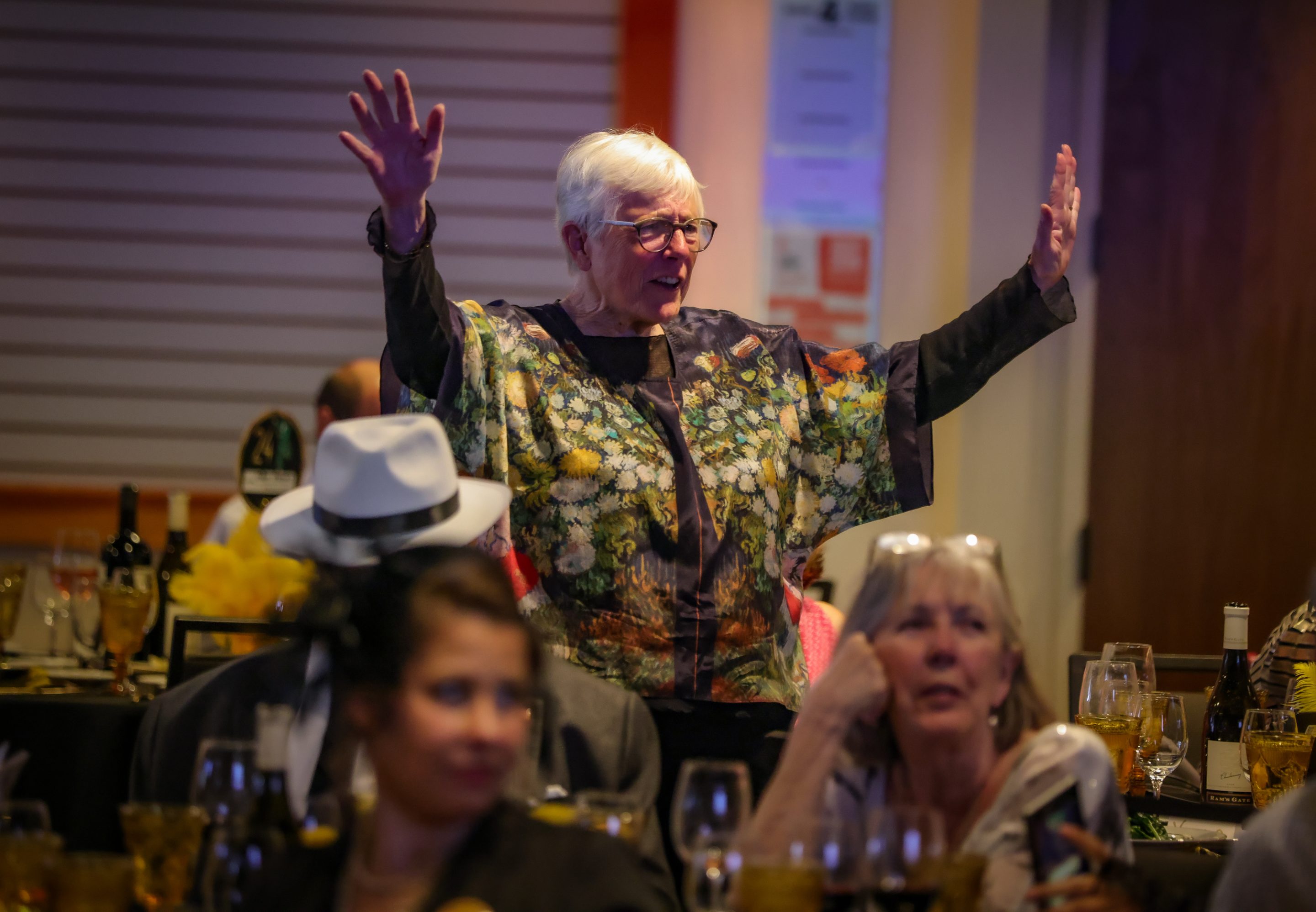 A woman is waving her arms at a dinner party hosted by The LIME Foundation of Santa Rosa.