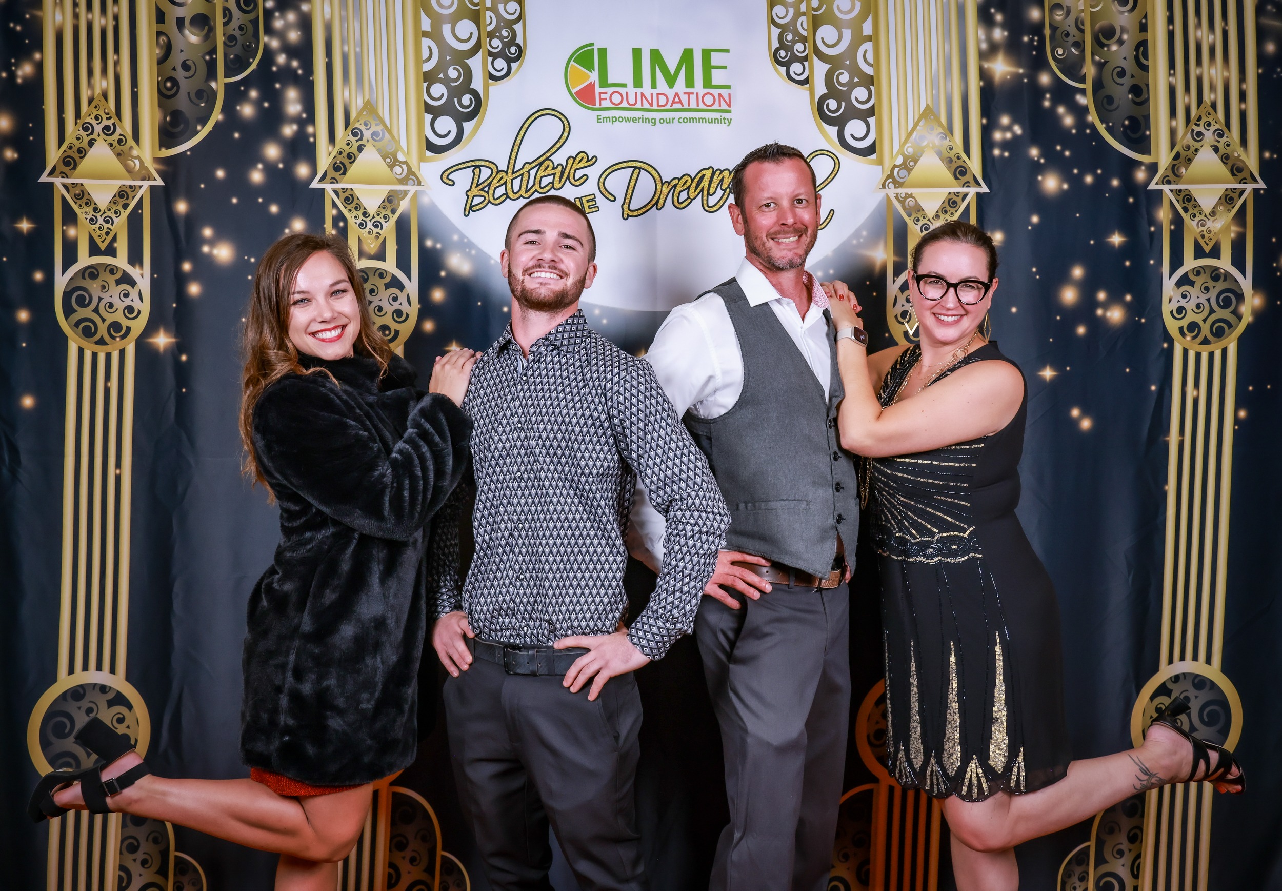 A group of people posing for a photo in front of a gilded backdrop at The LIME Foundation headquarters.
