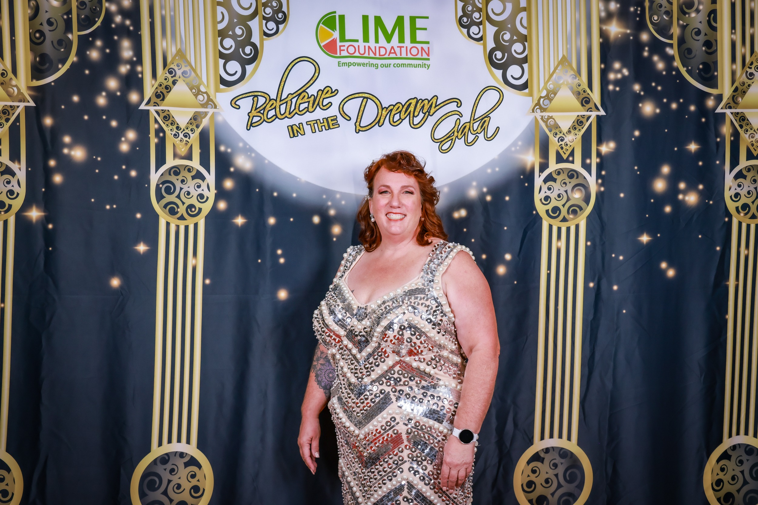 A woman in a sequin dress standing in front of a backdrop at The LIME Foundation of Santa Rosa.