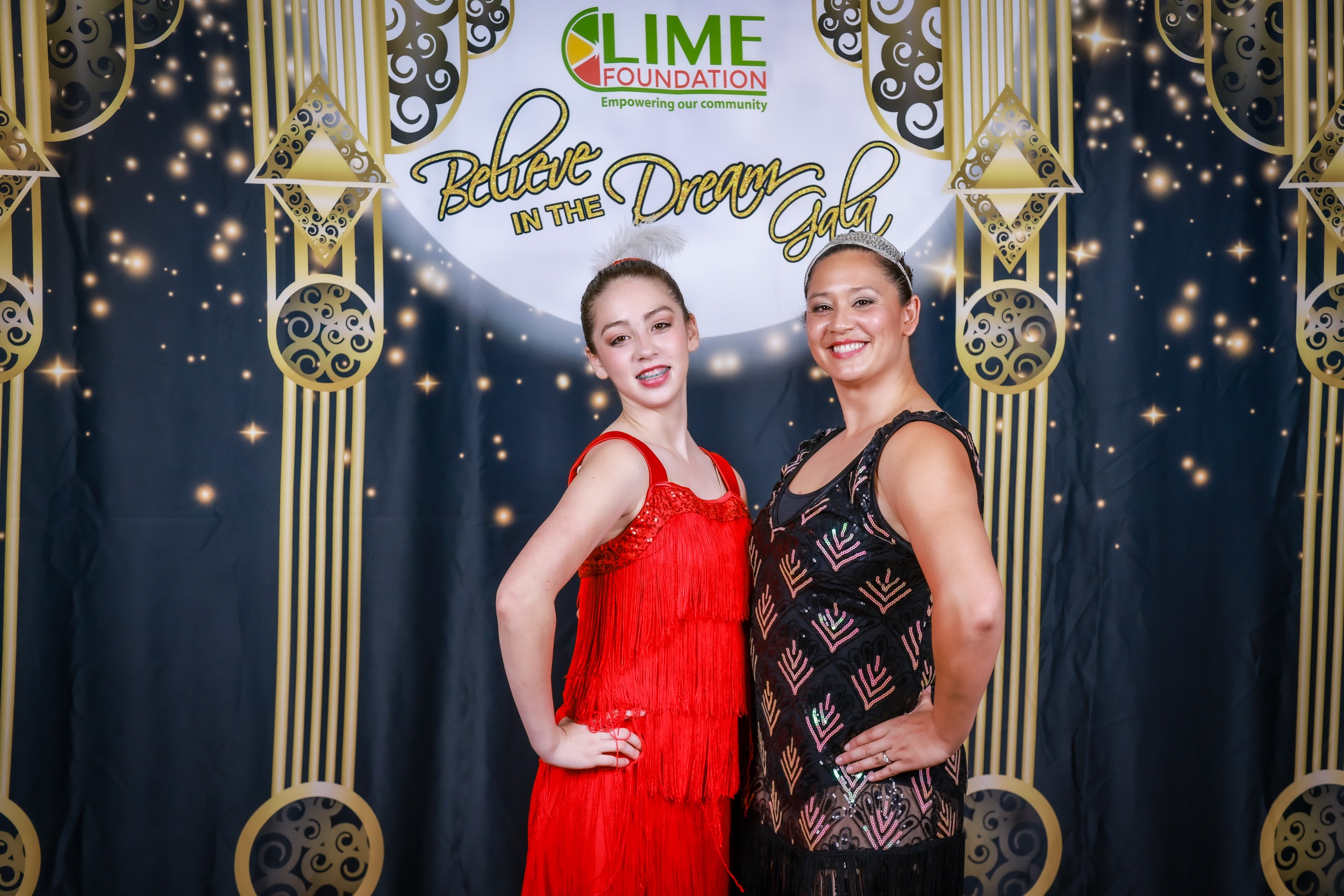 Two women pose for a photo in front of a gilded backdrop at the LIME Foundation event.