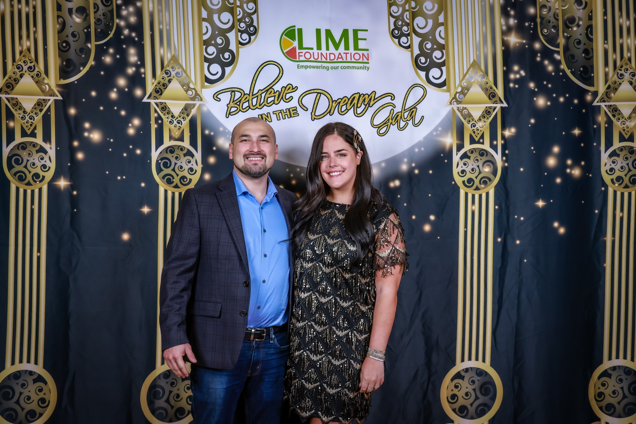 A man and woman posing for a photo in front of a backdrop sponsored by The LIME Foundation of Santa Rosa.