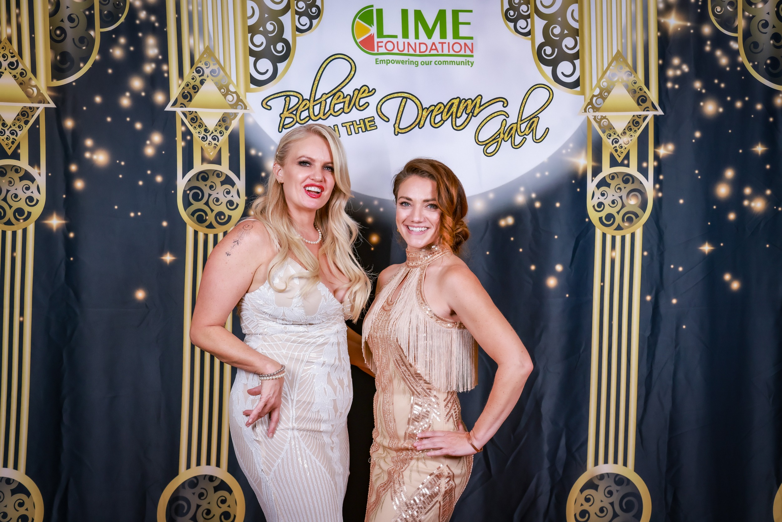 Two women posing for a photo at a Gatsby themed party hosted by The LIME Foundation.