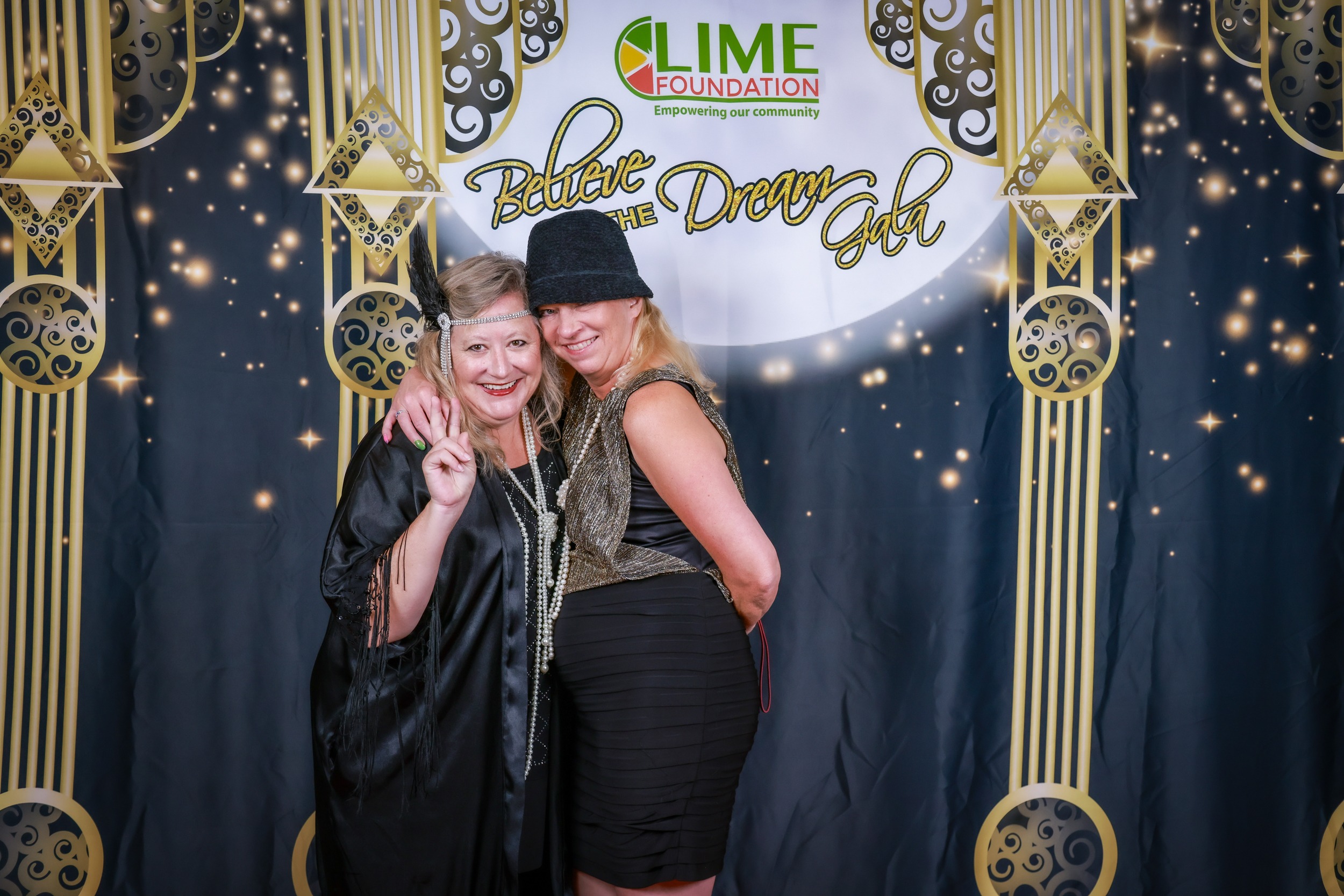 Two women posing for a photo in front of a backdrop at a Sonoma County non-profit organization event.