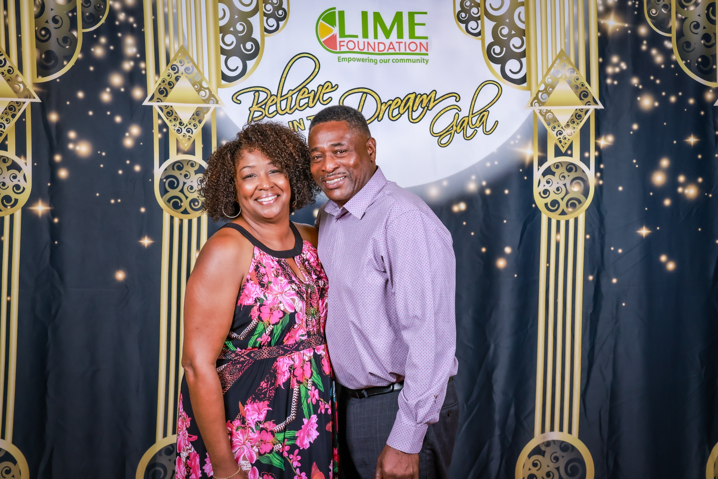 A man and woman posing for a photo in front of a backdrop at The LIME Foundation.