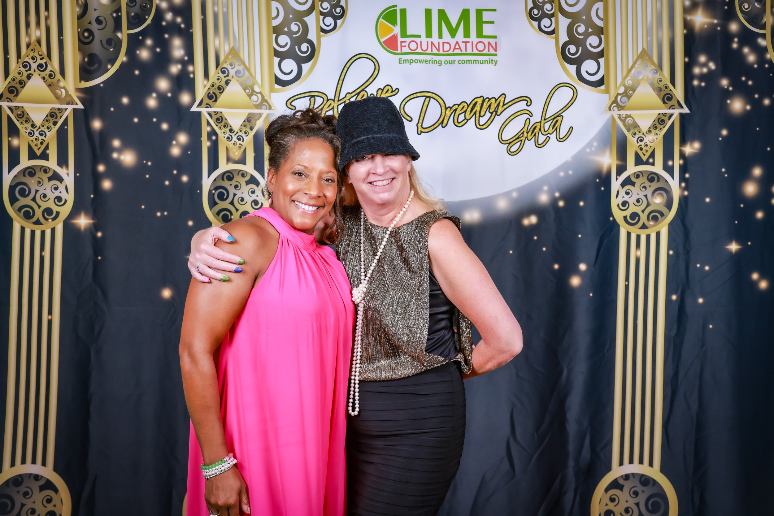 Two women posing for a photo at a photo booth sponsored by The LIME Foundation.