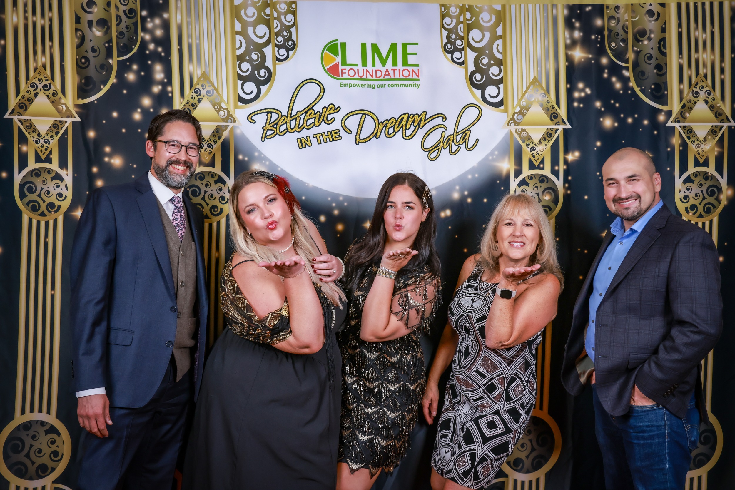 A group of people posing for a photo in front of a gilded backdrop at a Santa Rosa Non-Profit event.