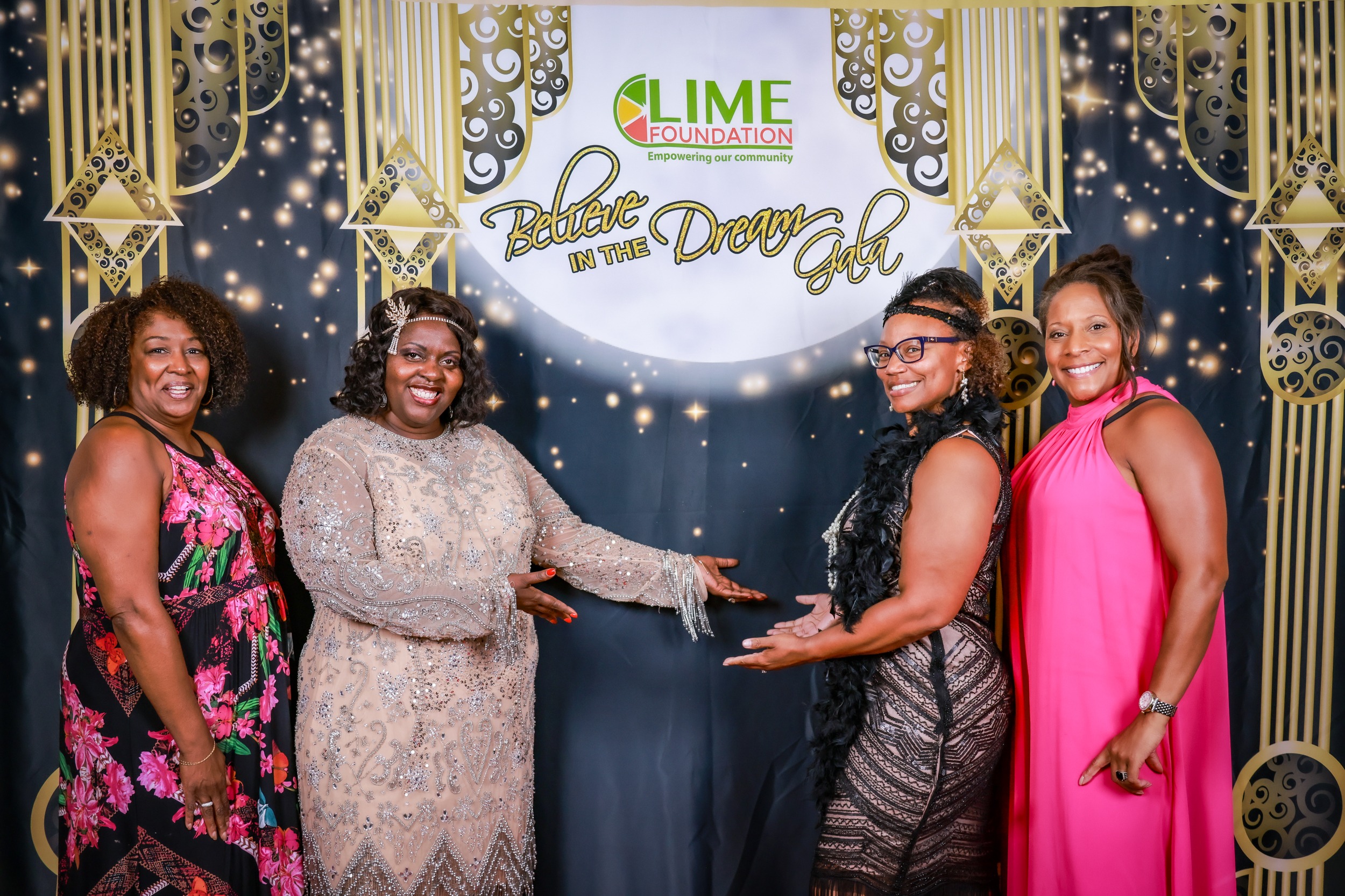 Four women posing for a picture in front of a backdrop at the LIME Foundation.