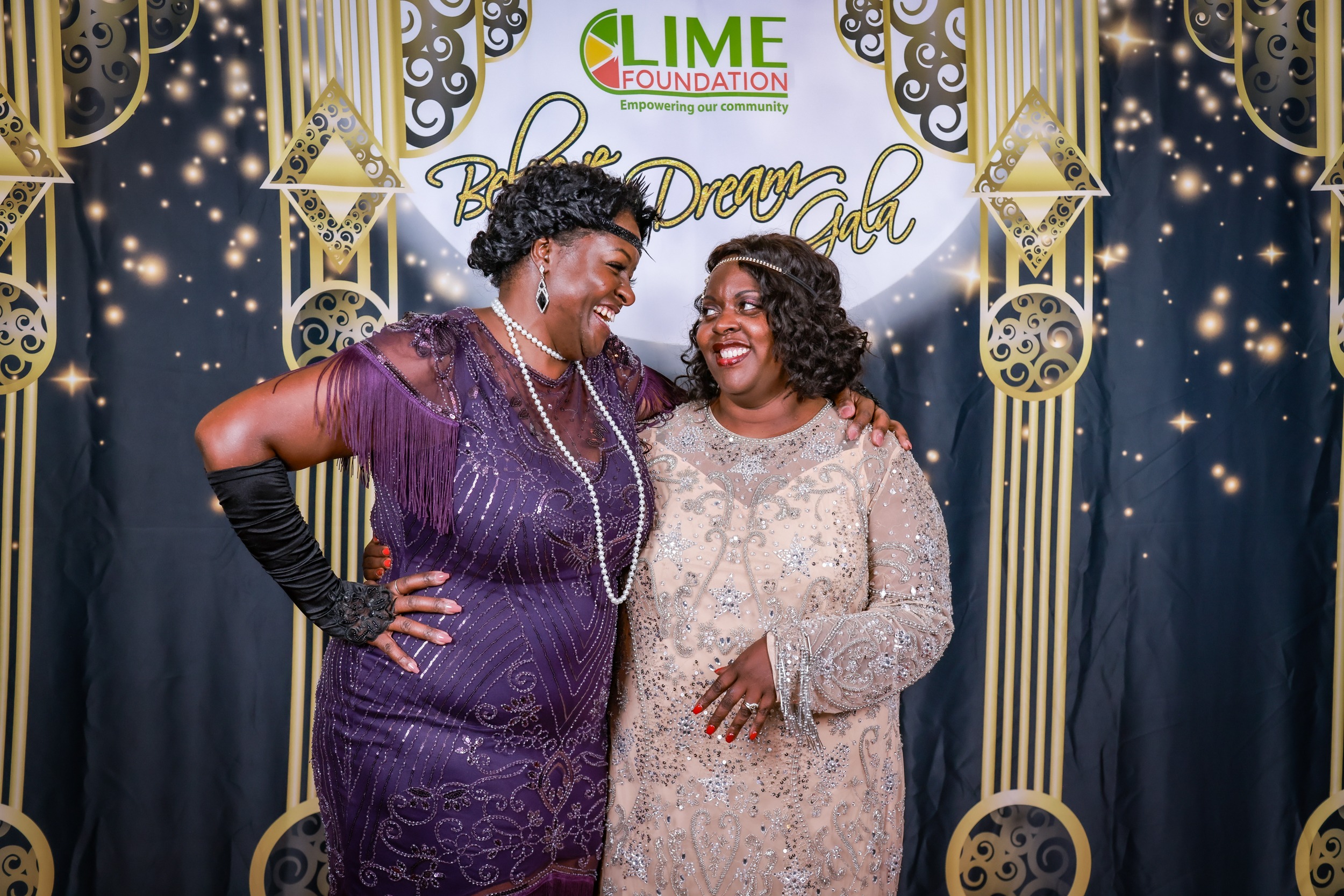 Two women posing for a photo at a 1920's themed party hosted by LIME Foundation.