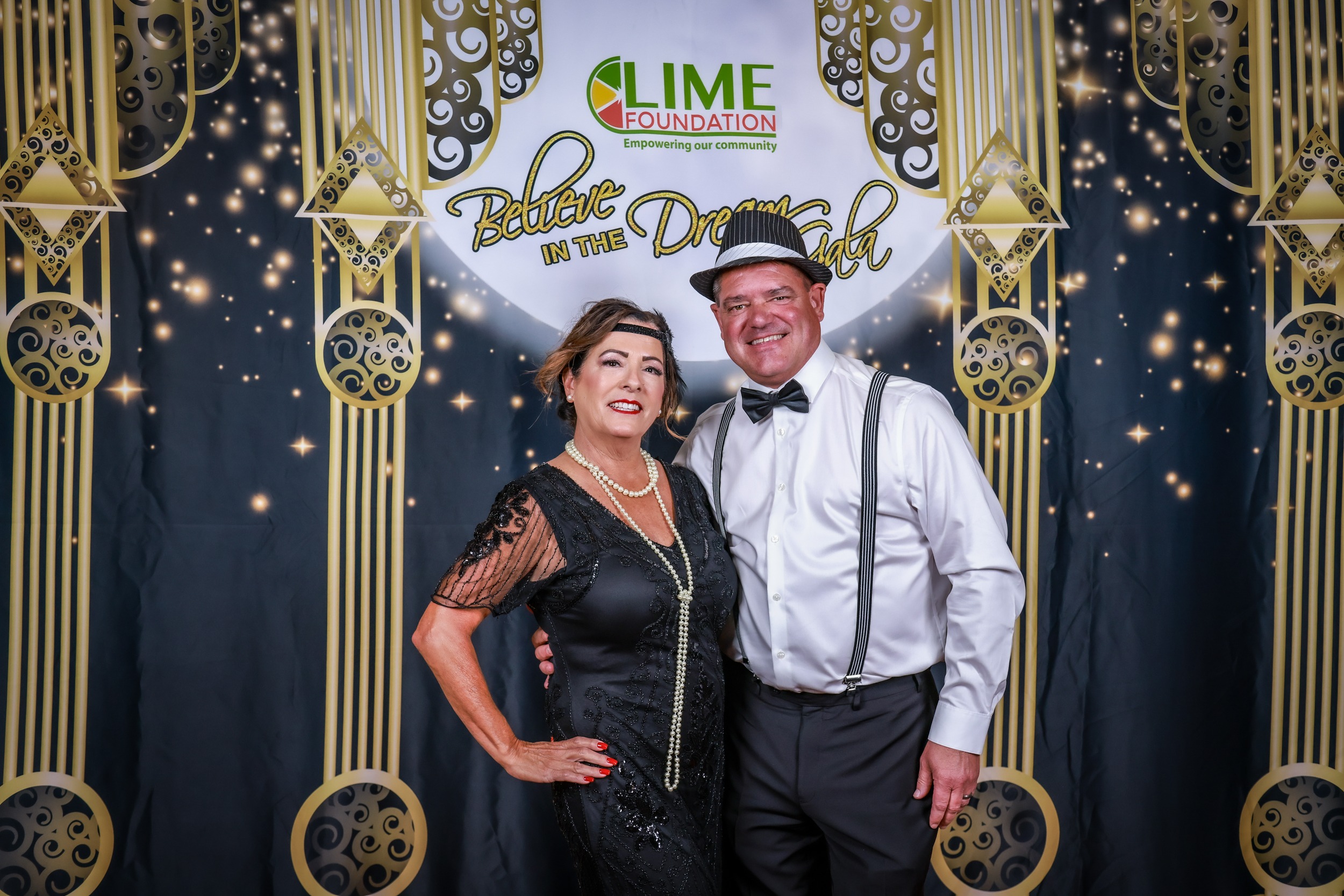 A man and woman posing for a photo in front of a gilded backdrop at The LIME Foundation of Santa Rosa.