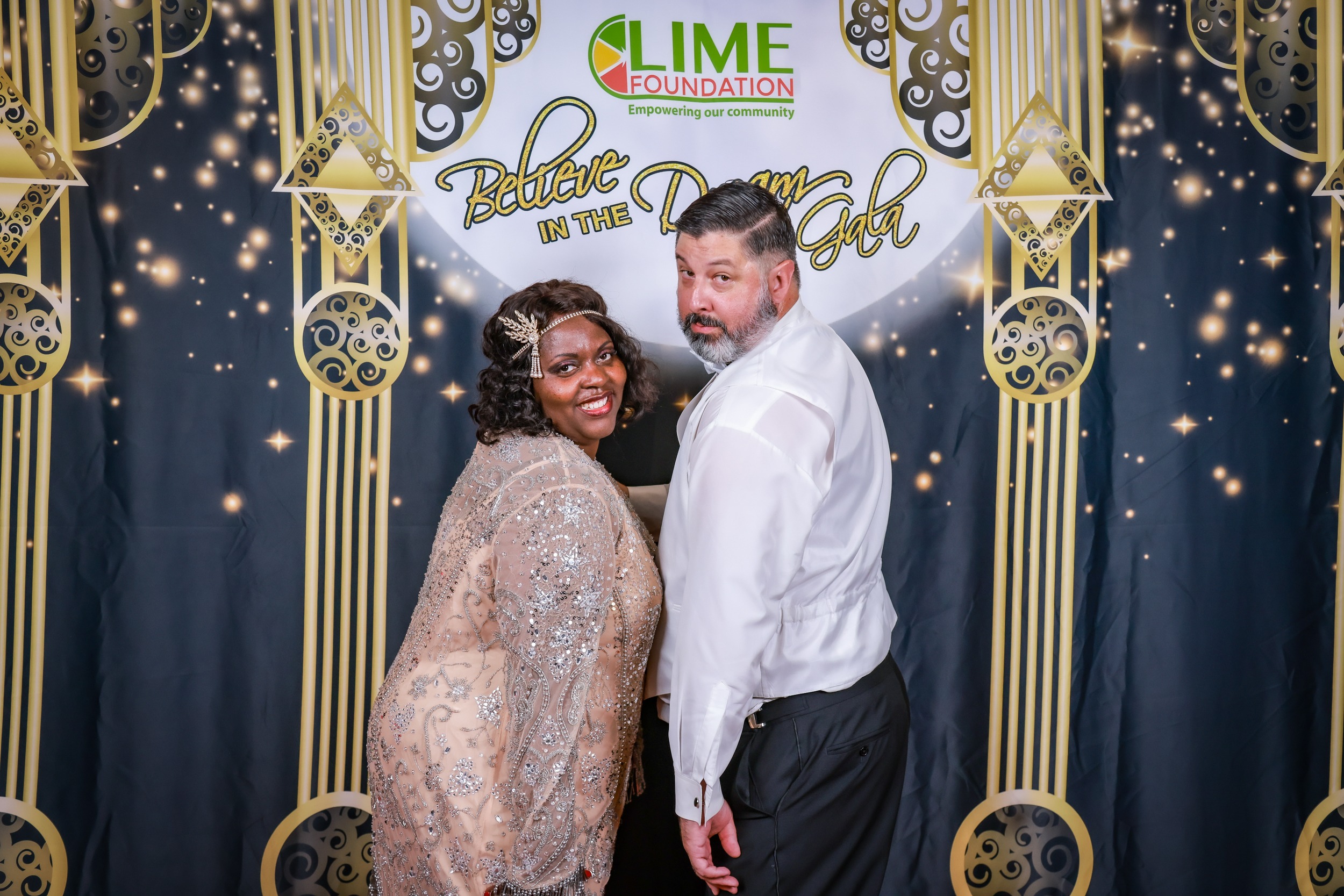 A man and woman posing in front of a photo booth sponsored by The LIME Foundation of Santa Rosa.