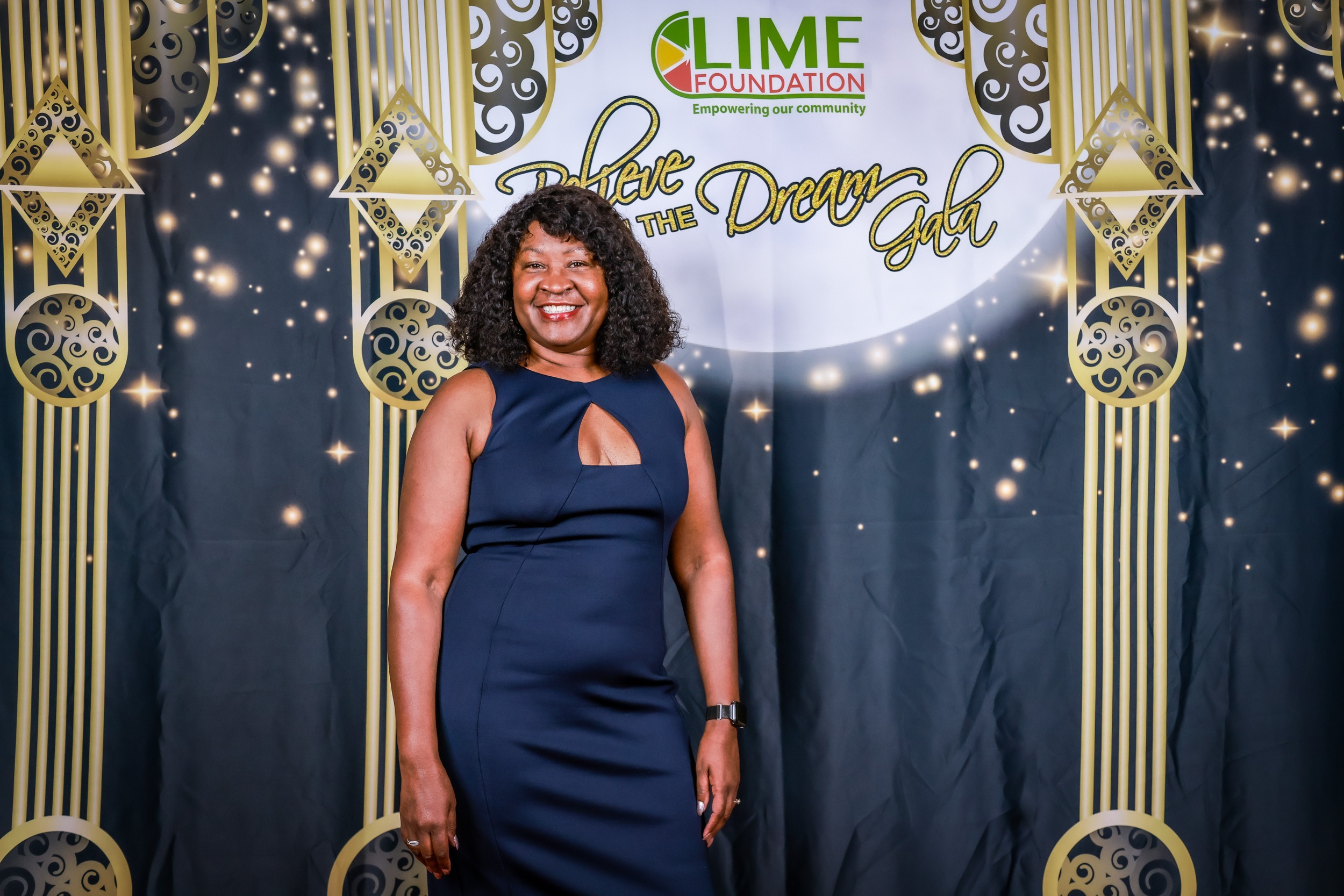 A woman in a black dress standing in front of The LIME Foundation backdrop.