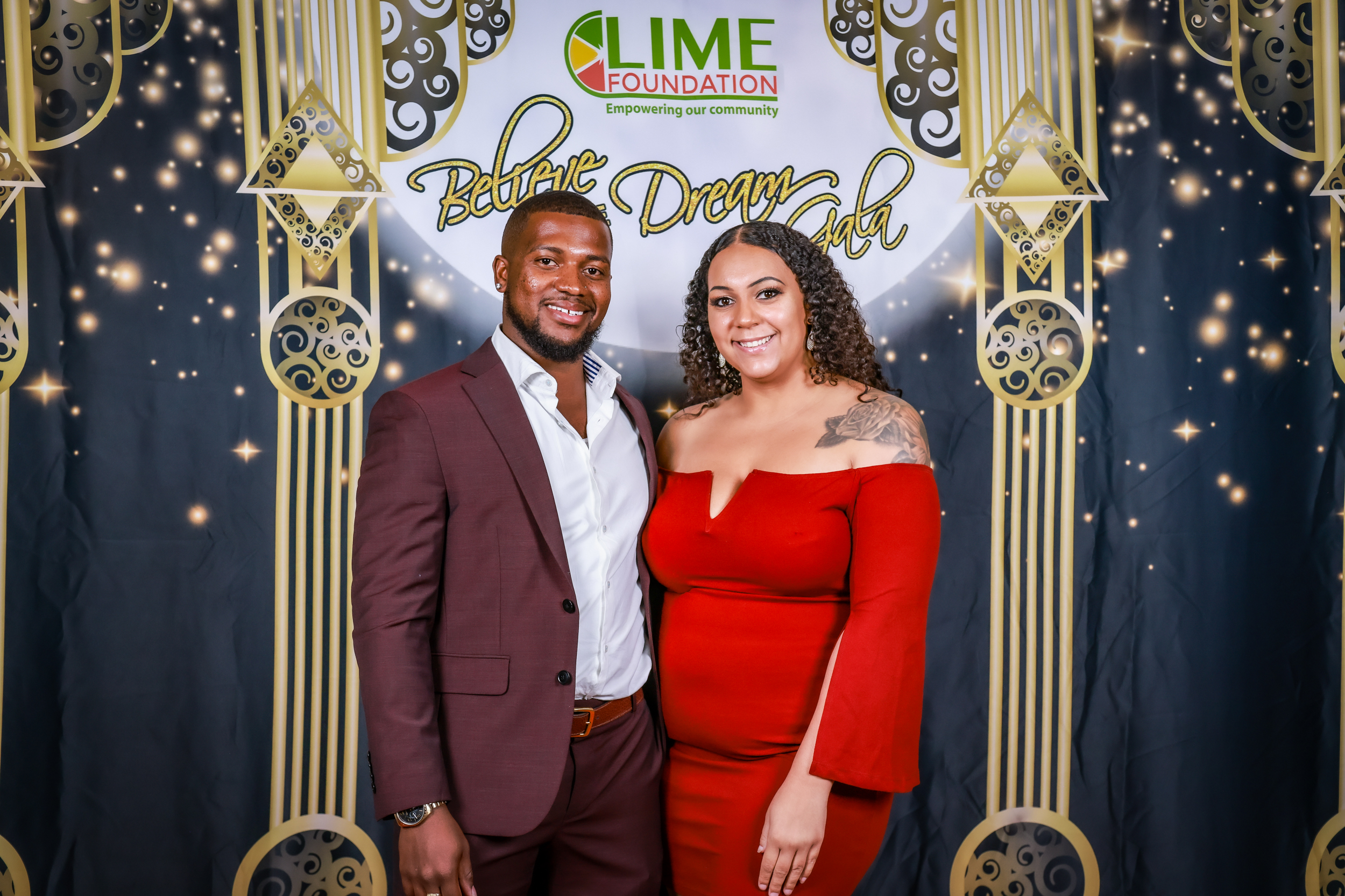 A man and woman posing for a photo in front of a gold backdrop at The LIME Foundation of Santa Rosa.