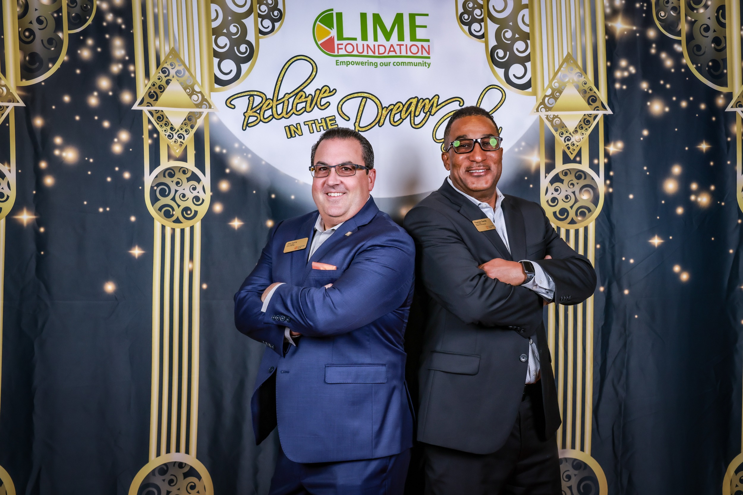 Two men in suits standing in front of a backdrop at The LIME Foundation fundraiser event.
