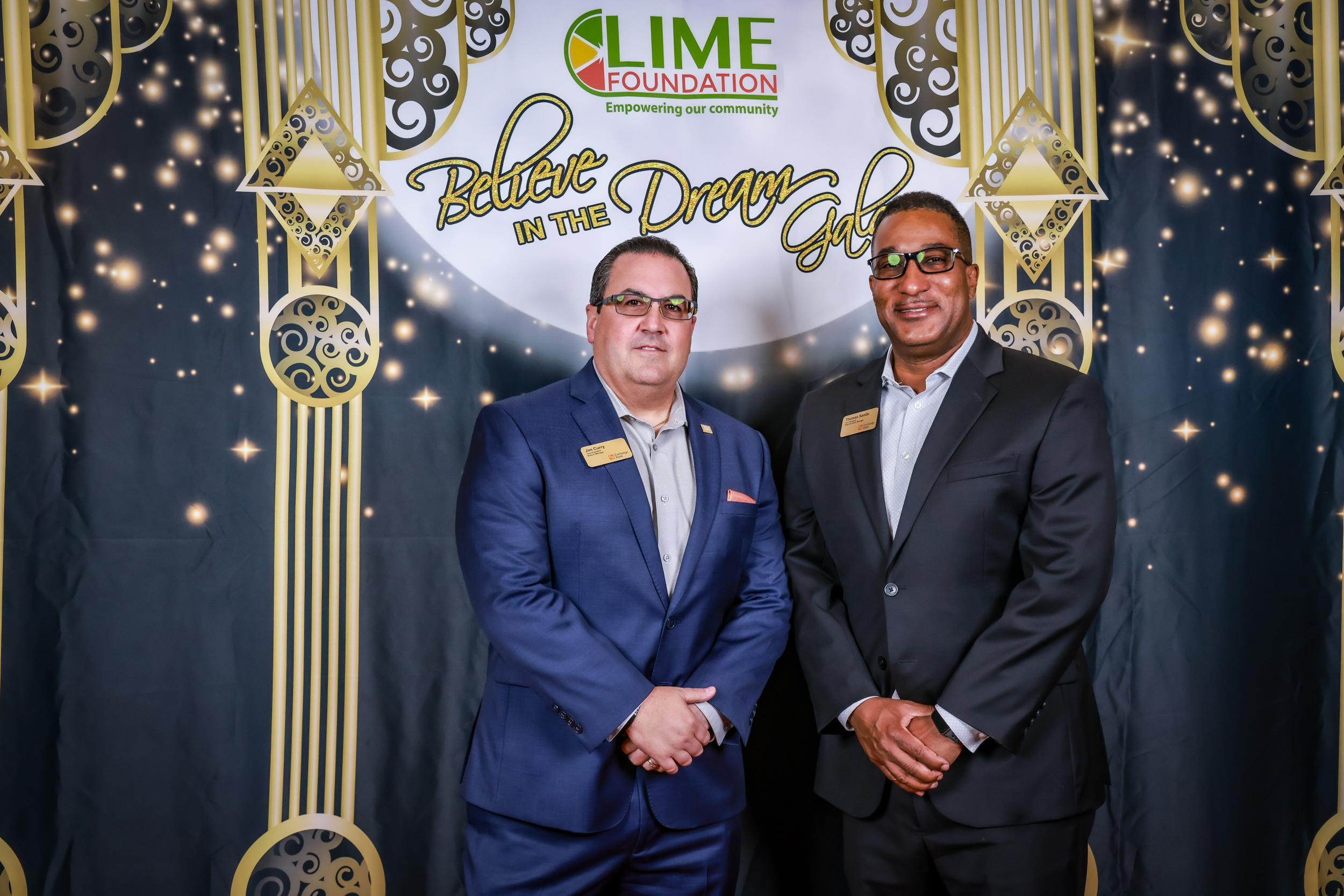 Two men in suits standing in front of a gold backdrop at The LIME Foundation of Santa Rosa.