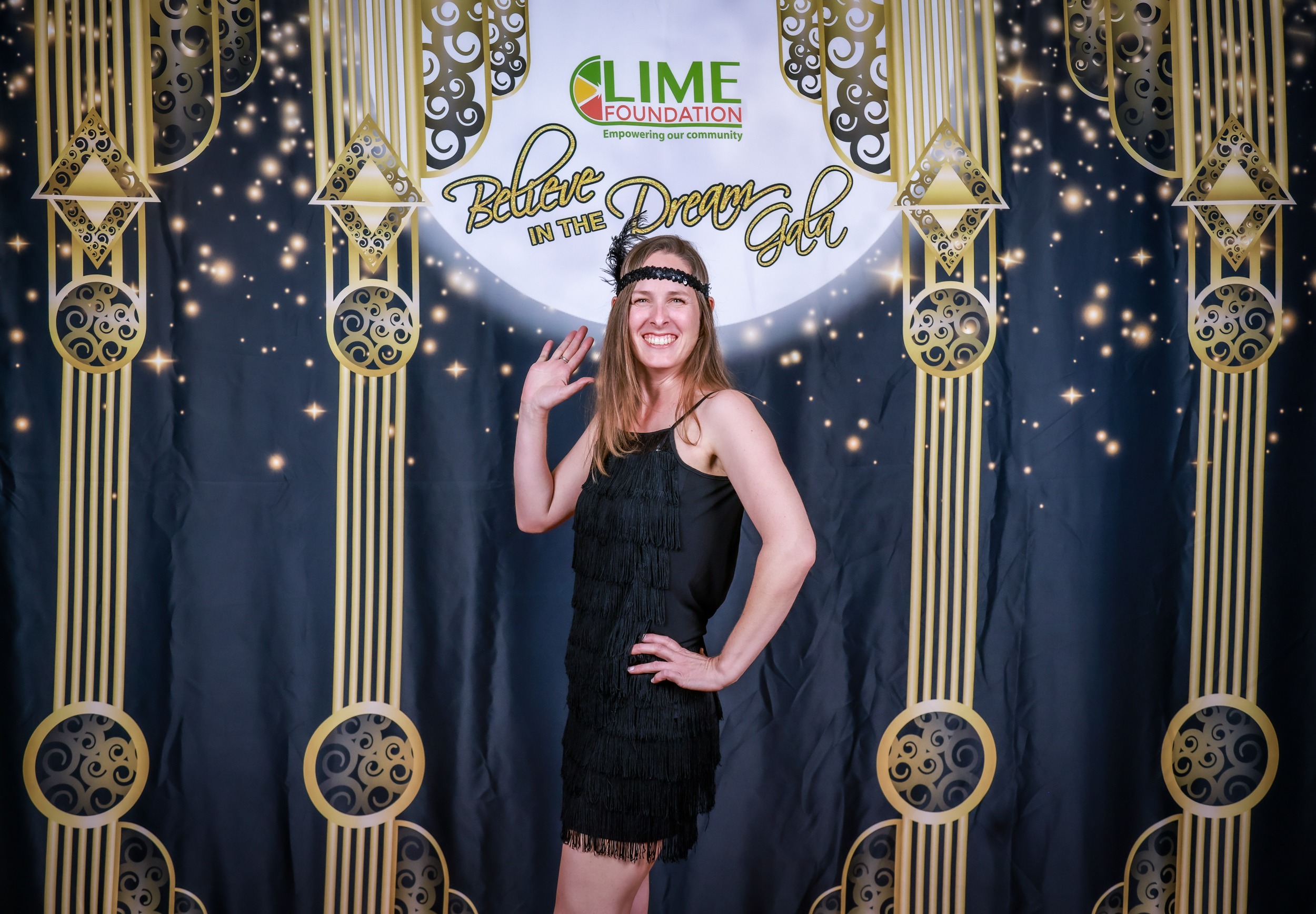 A woman is posing for a photo in front of a gilded backdrop at The LIME Foundation of Santa Rosa.