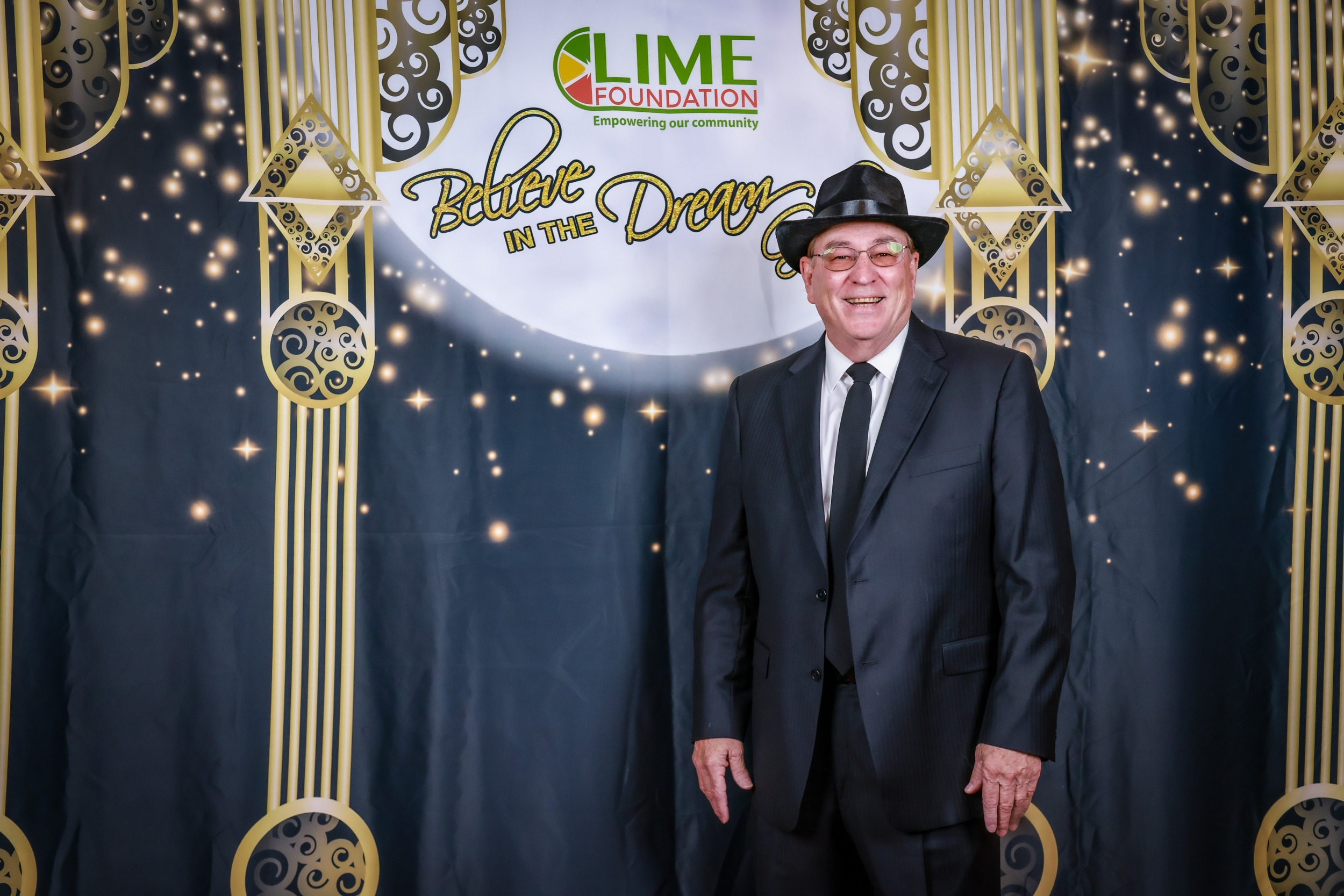 A man in a hat standing in front of the backdrop representing The LIME Foundation of Santa Rosa.