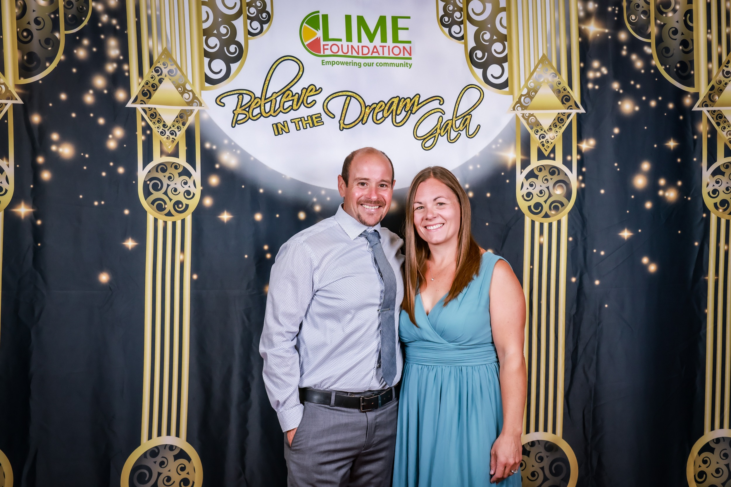 A man and woman are posing in front of a photo booth at The LIME Foundation of Santa Rosa.