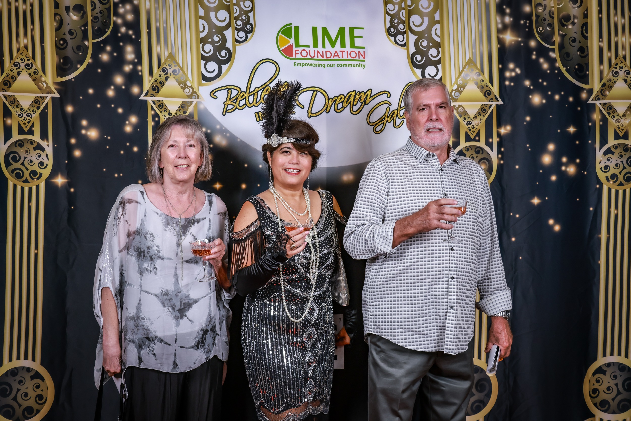 Three people posing for a photo at a 1920's themed event hosted by the LIME Foundation.