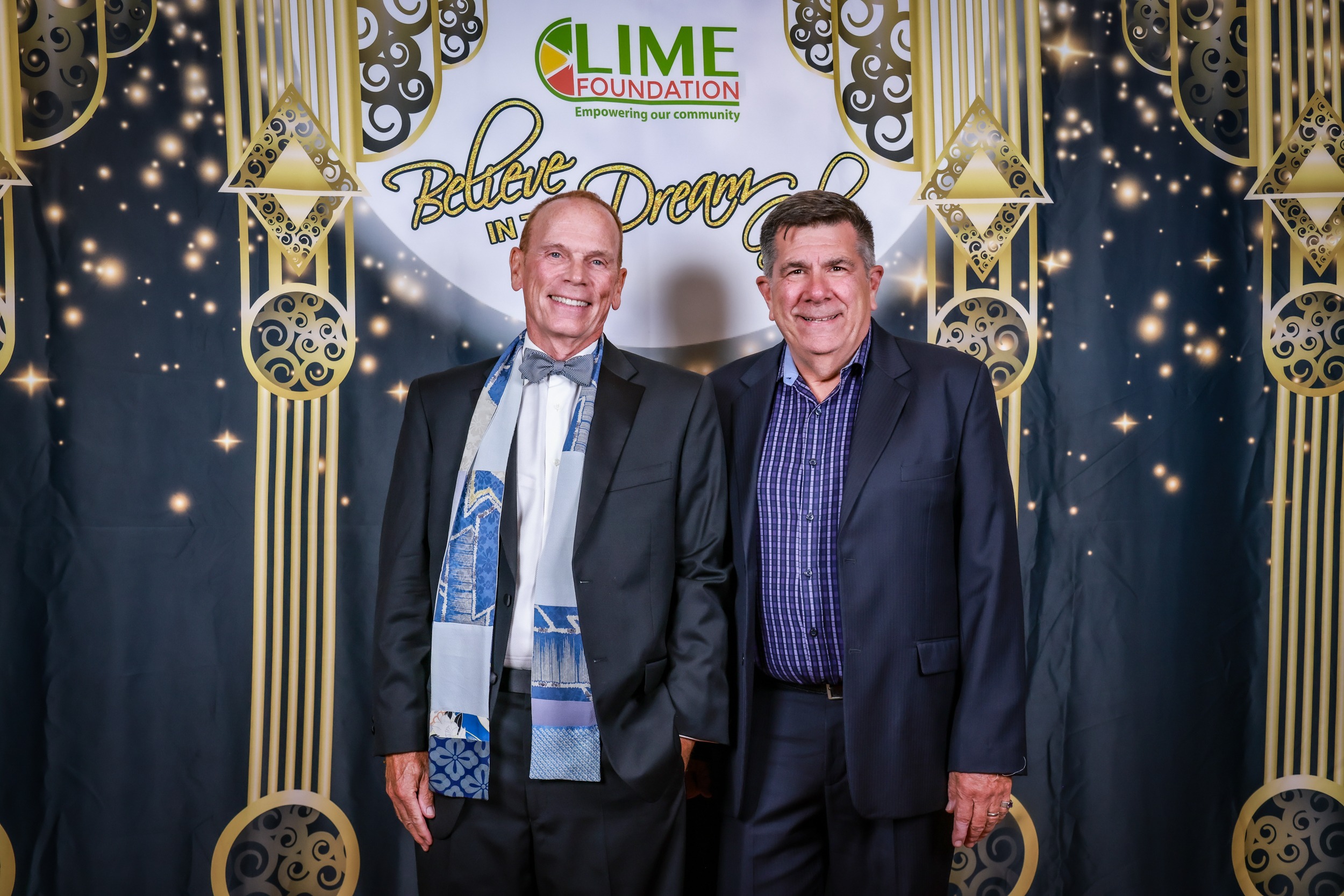 Two men posing for a picture in front of The LIME Foundation's backdrop.