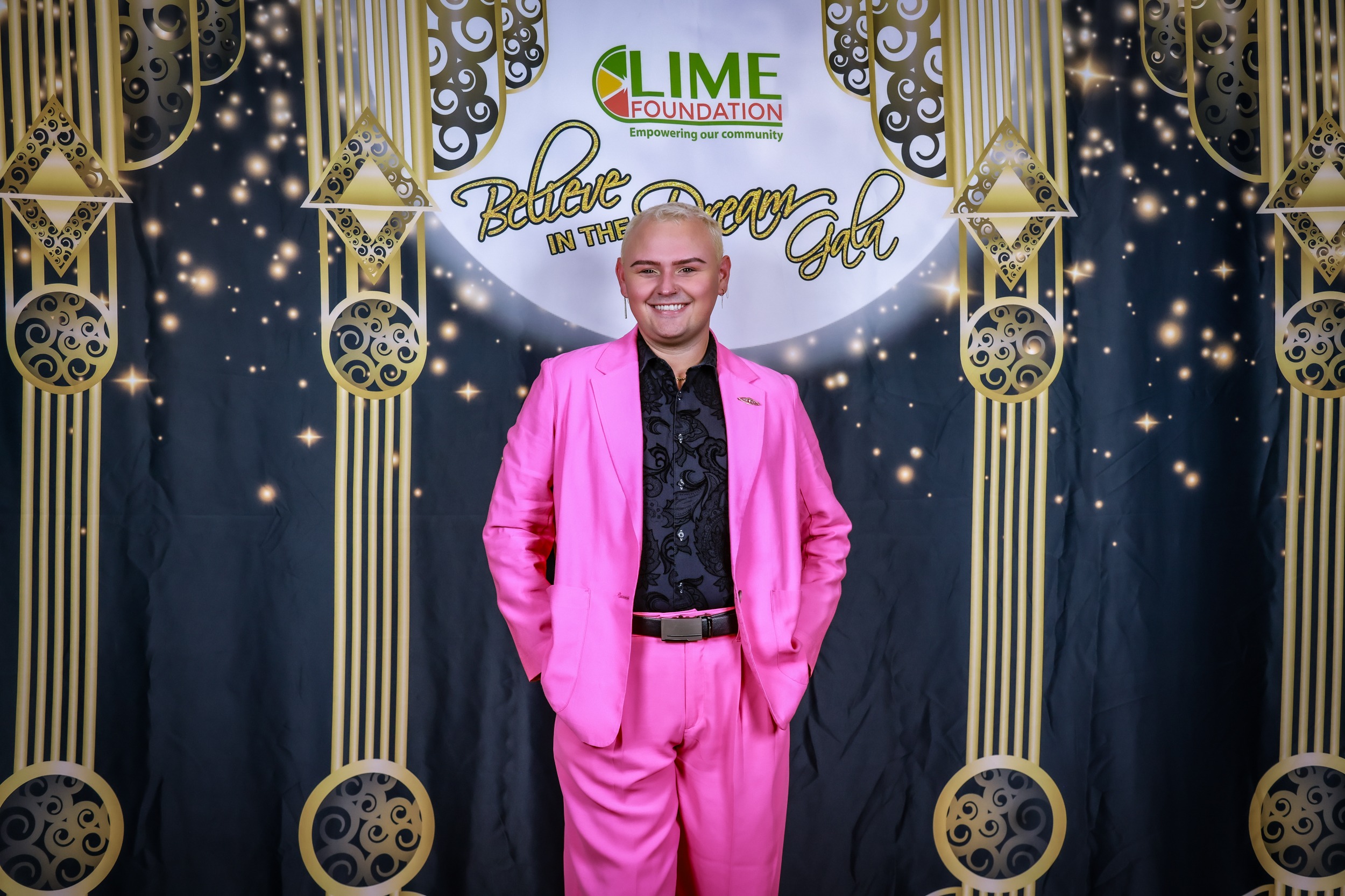 A man in a pink suit stands in front of a gold backdrop at the LIME Foundation, a Sonoma County non-profit organization.