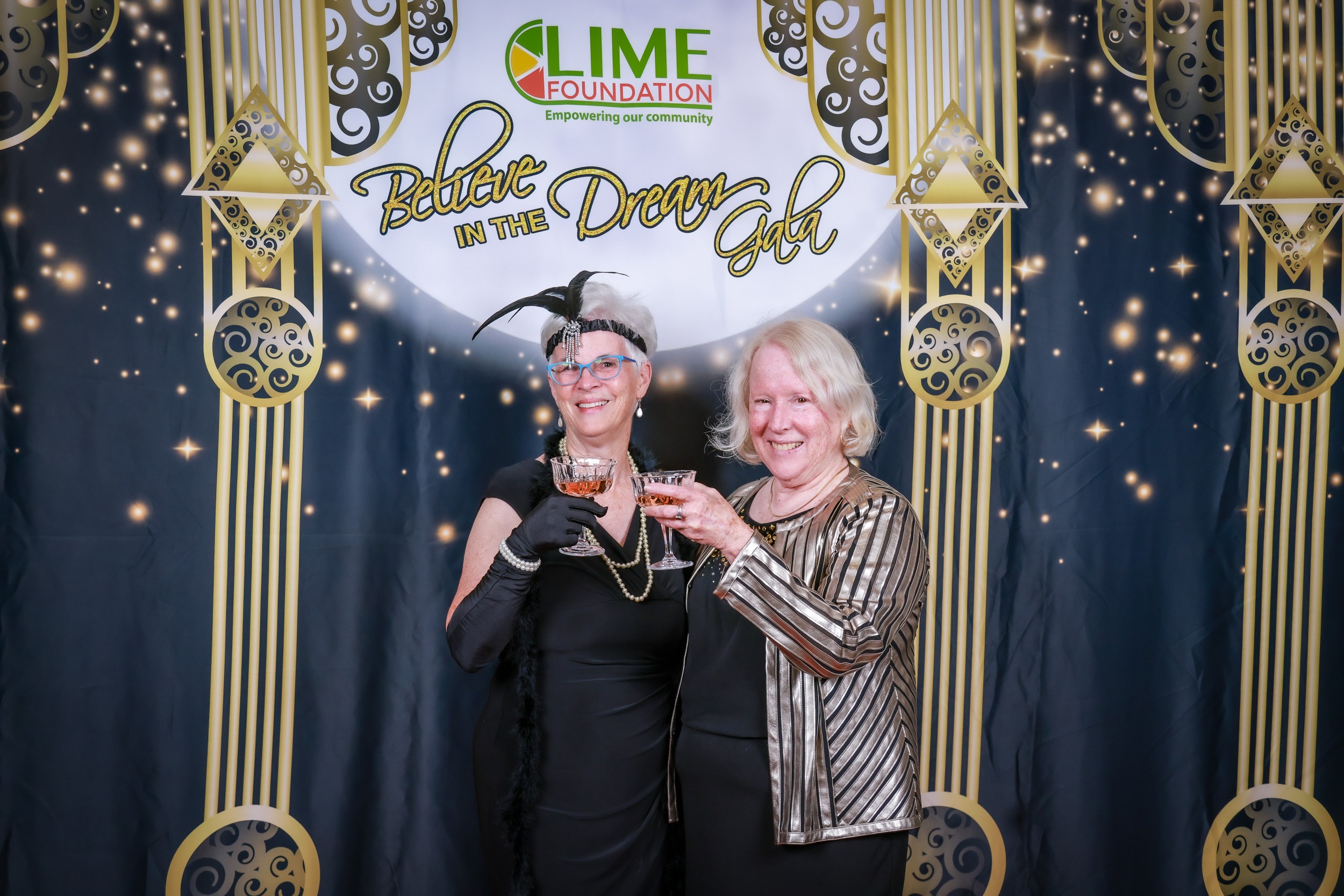 Two women posing for a photo in front of a gilded backdrop at The LIME Foundation event.